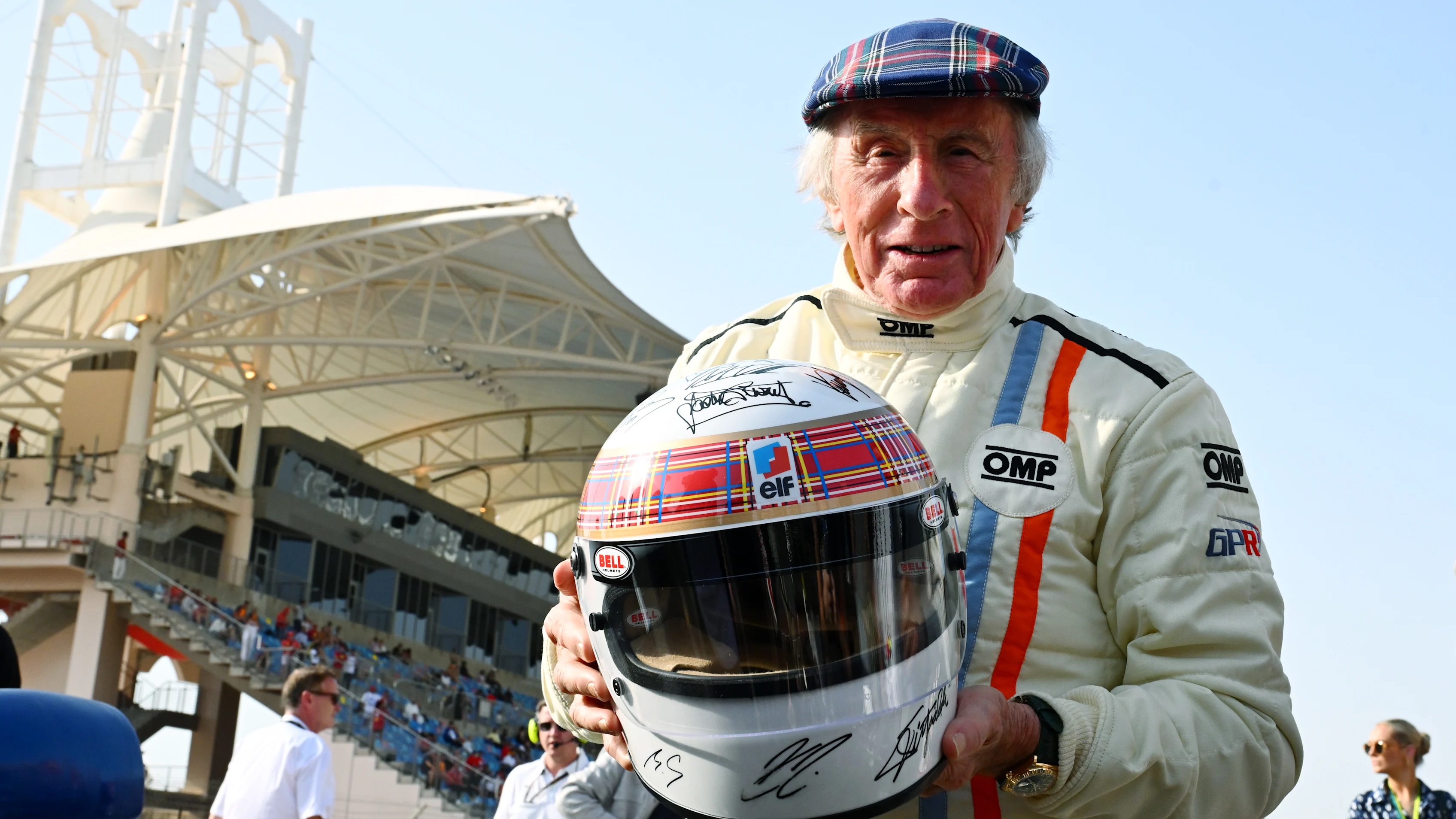 Sir Jackie Stewart dan topi keledar Tartan tandatangannya. Leret untuk lebih banyak gambar